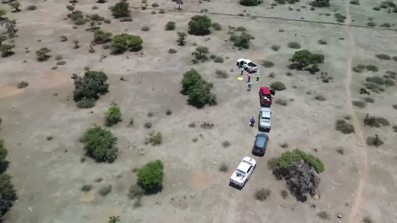 Brigada de topografía y vehículos en terreno rocoso, vista desde dron