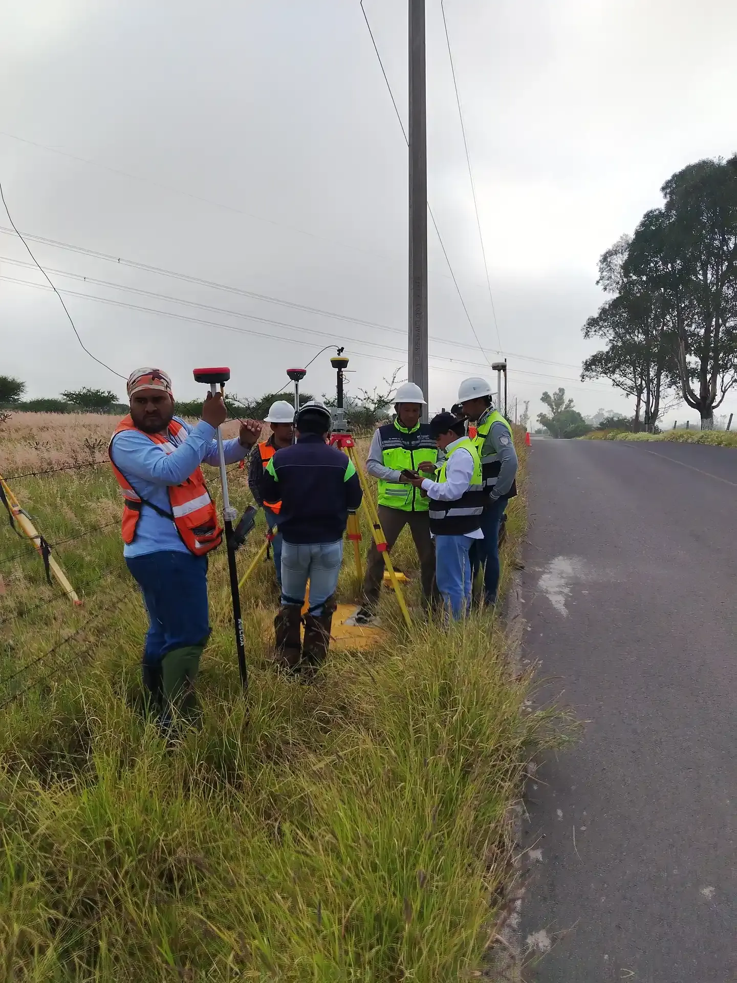 Brigada con GNSS caminando por el camino, de espaldas