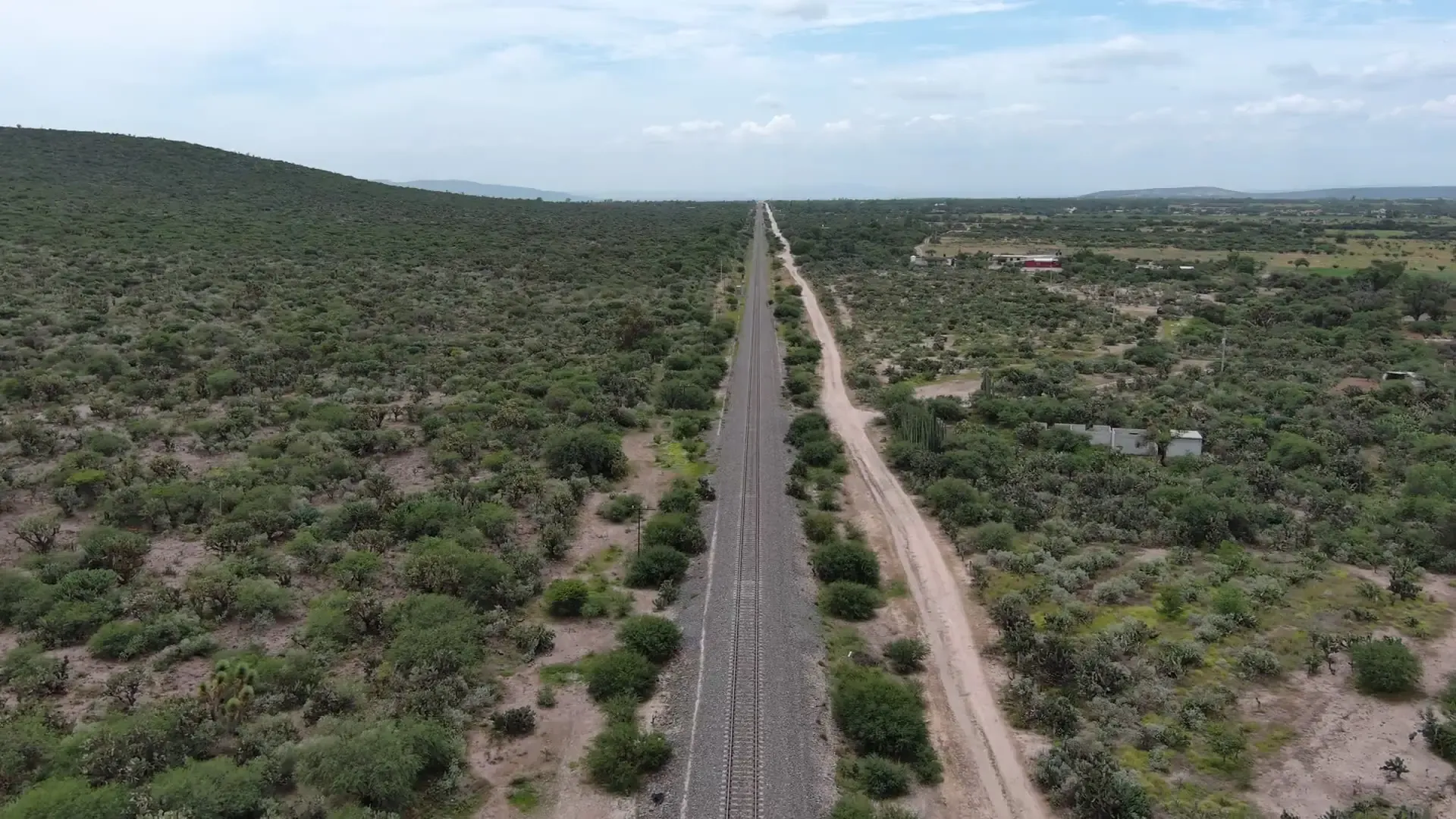 Vía férrea recta vista desde un dron, entre campos y cerros